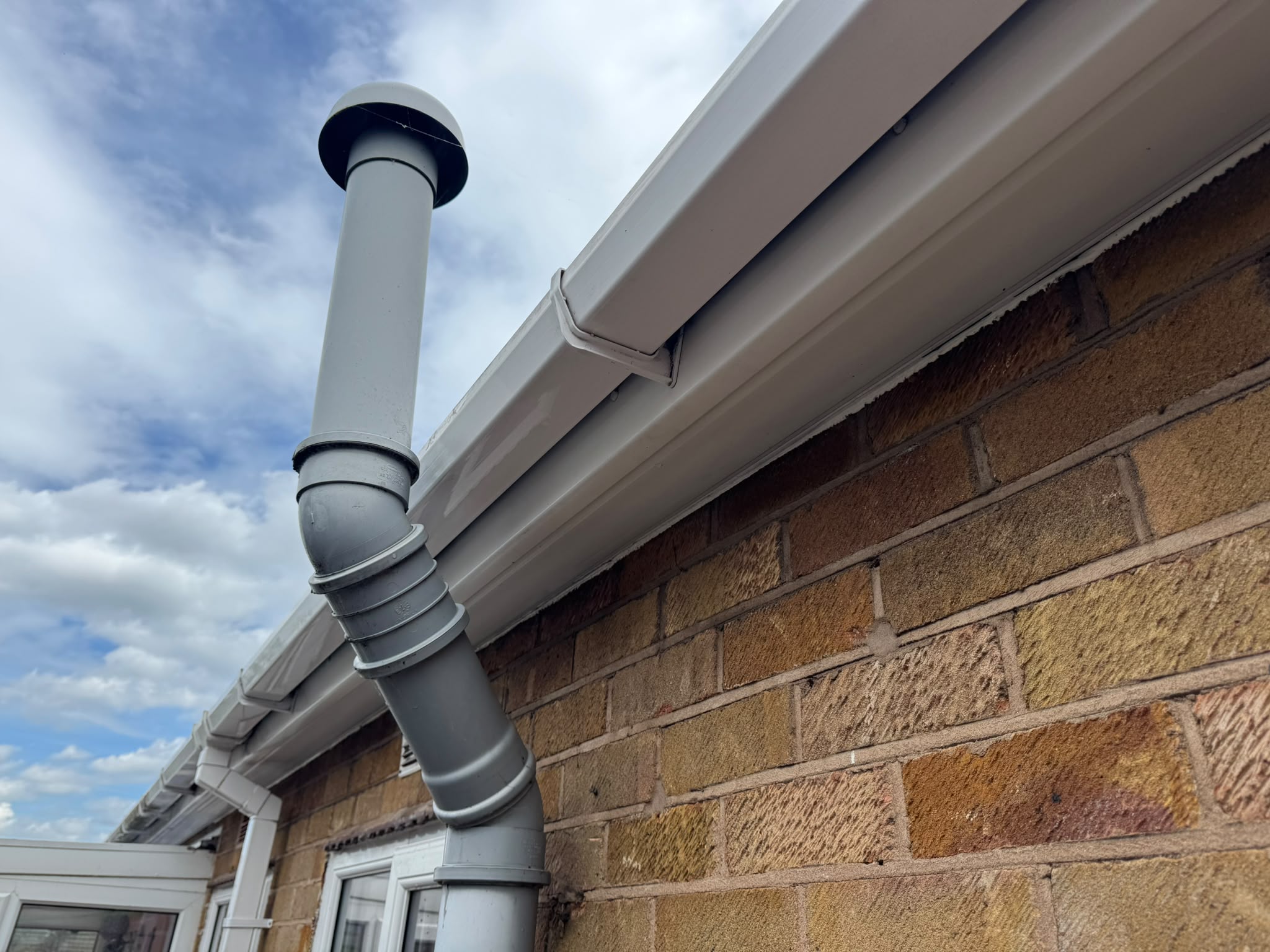 Gleaming white gutter, fascia and downpipe after cleaning
